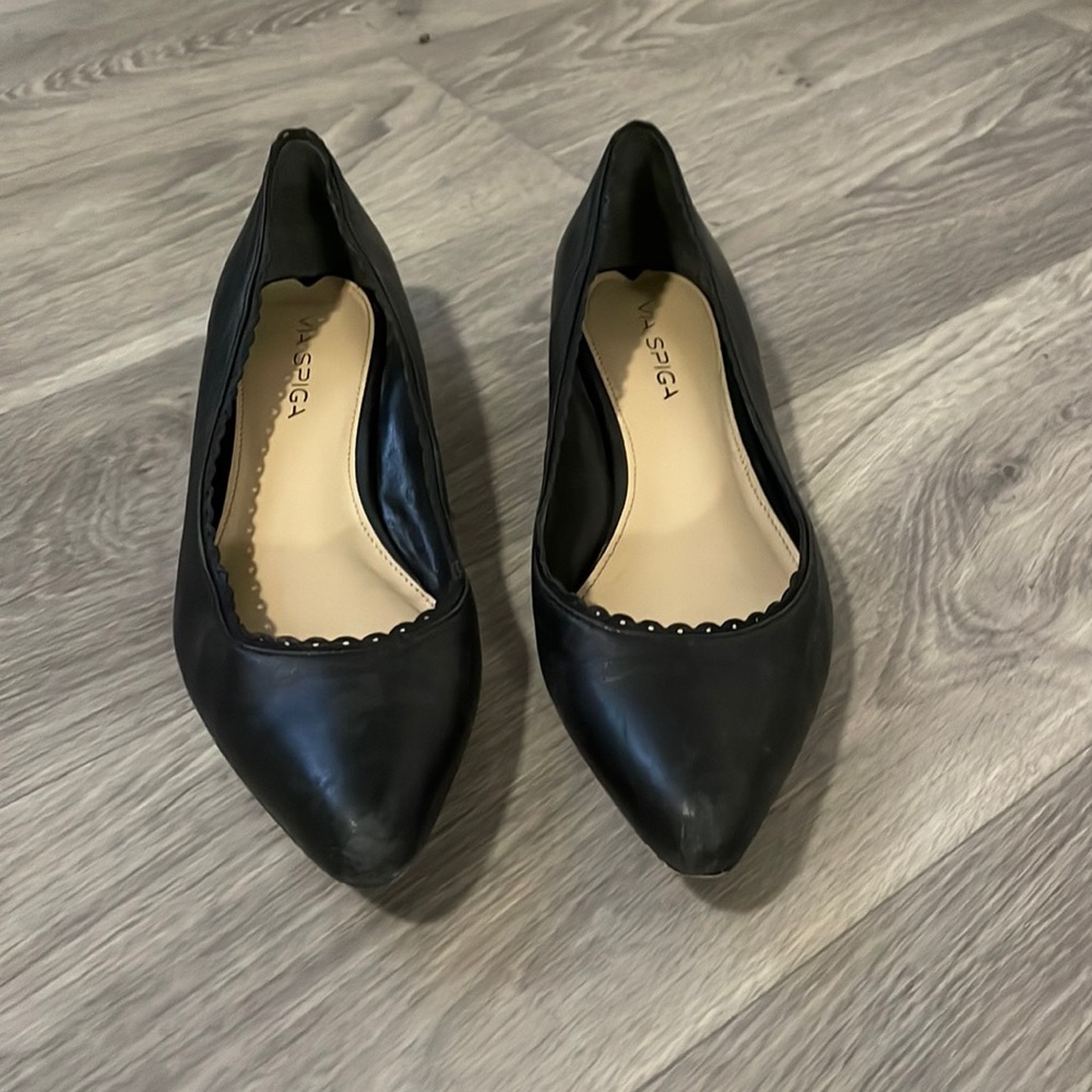 Black leather pointed toe flats. With scolloped detail